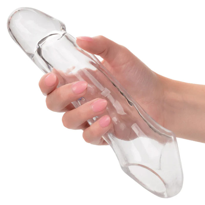 Hand holdings a clear penis sleeve with scrotum strap on a white background