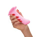 Hand holding a smooth pink silicone dildo on a white background