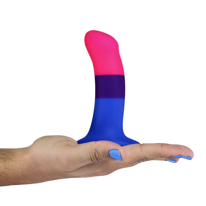 Silicone dildo with pink top and blue bottom on palm of hand