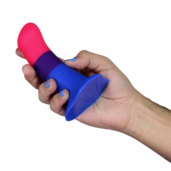 Hand holding a silicone dildo with pink top and blue bottom on a white background