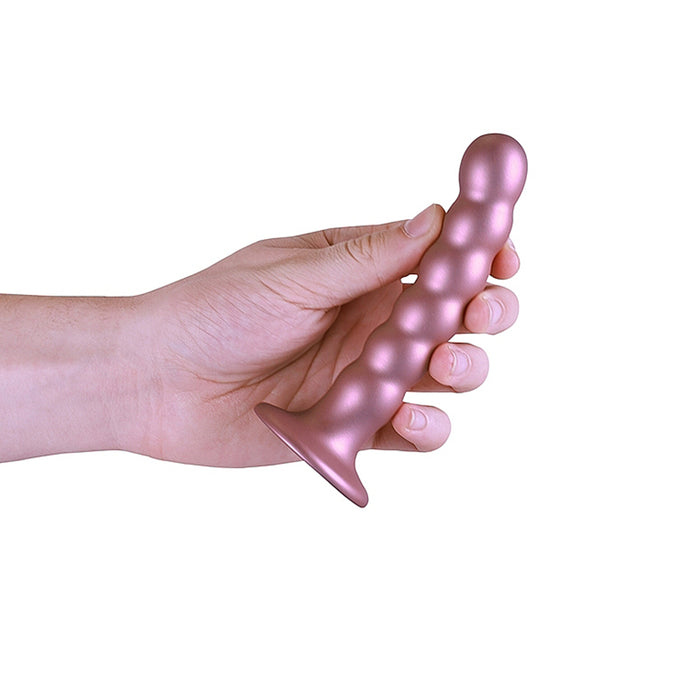 Hand holding a pink beaded dildo with suction cup base on a white background