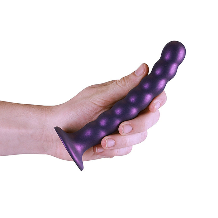 Hand holding a purple beaded dildo with suction cup base on a white background